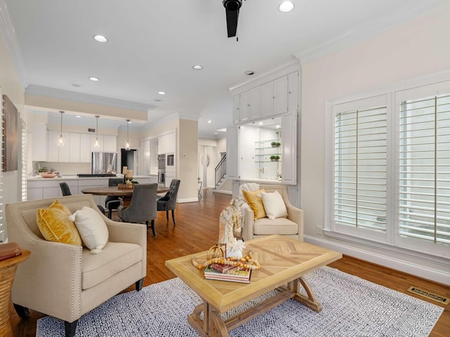 living room featuring wood finished floors, baseboards, and ornamental molding