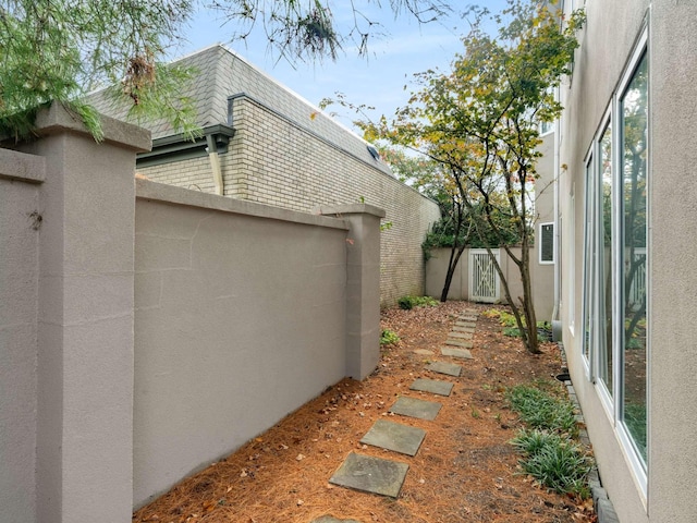 view of side of property featuring mansard roof, fence, and stucco siding