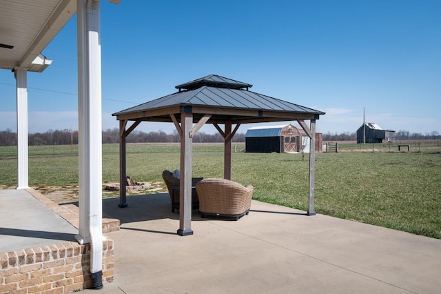 view of patio featuring a gazebo, a rural view, an outdoor structure, and a shed