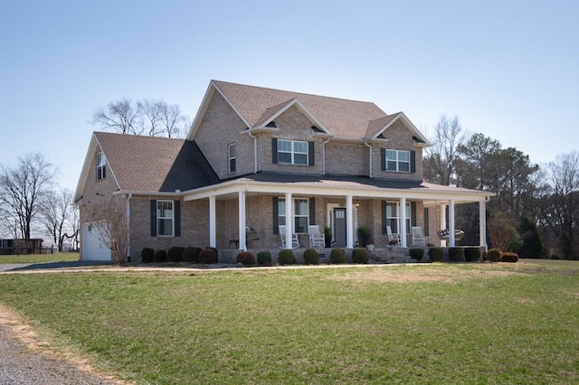 view of front of property featuring brick siding, a front lawn, a porch, roof with shingles, and a garage