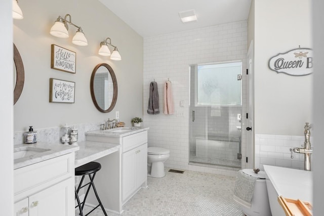 bathroom with tile patterned floors, toilet, a stall shower, tile walls, and vanity