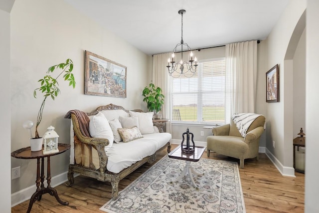 living room with baseboards, arched walkways, a notable chandelier, and wood finished floors