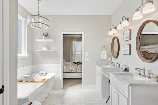 ensuite bathroom featuring tile patterned flooring, a chandelier, ensuite bathroom, tile walls, and a sink