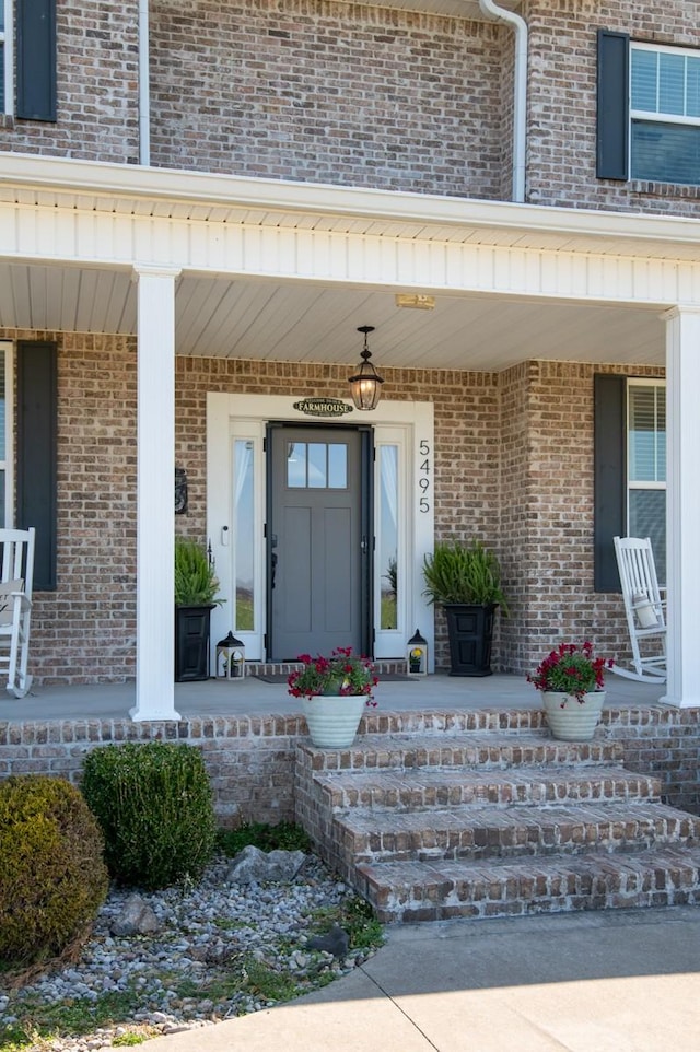 property entrance with brick siding and covered porch