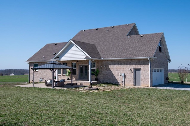 back of house with an attached garage, a yard, french doors, a patio area, and brick siding