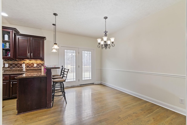 kitchen with tasteful backsplash, baseboards, pendant lighting, a breakfast bar area, and light wood-type flooring