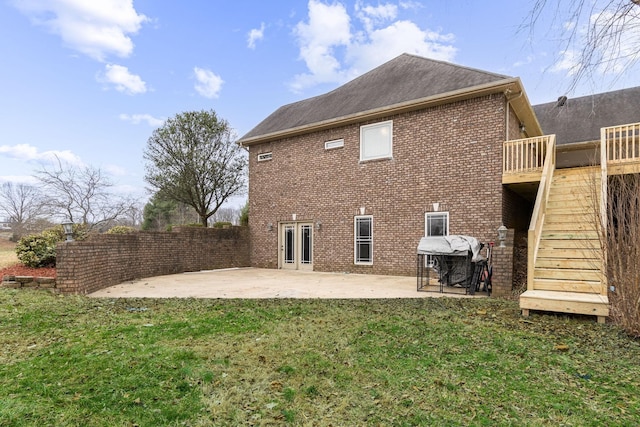 rear view of property featuring brick siding, stairs, roof with shingles, a yard, and a patio area