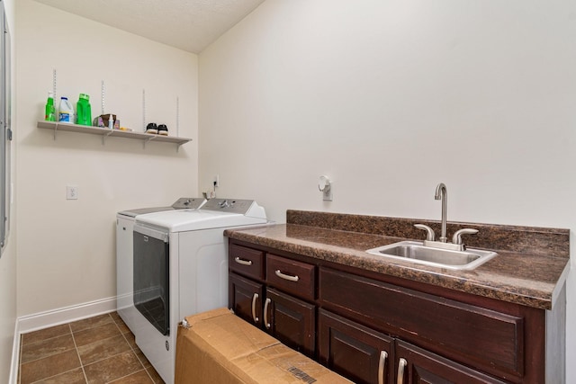 clothes washing area featuring a sink, baseboards, dark tile patterned floors, cabinet space, and separate washer and dryer