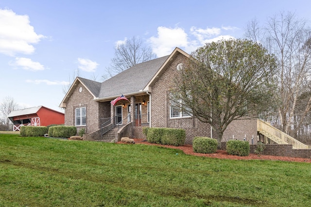 view of front of house featuring brick siding, roof with shingles, and a front yard