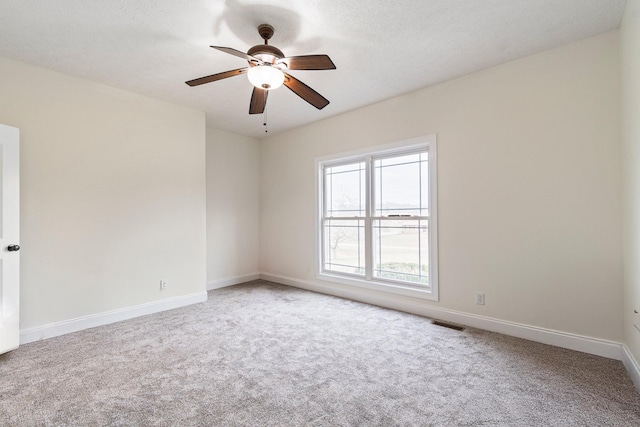 carpeted spare room featuring visible vents, baseboards, a textured ceiling, and a ceiling fan