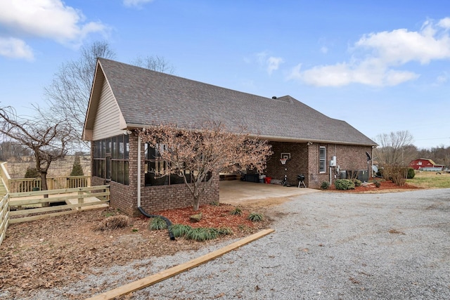 view of front facade featuring an attached carport, brick siding, driveway, and a sunroom