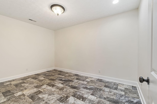 unfurnished room with visible vents, a textured ceiling, and baseboards