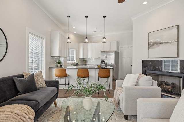 living room featuring crown molding, light wood-style flooring, recessed lighting, and a high end fireplace