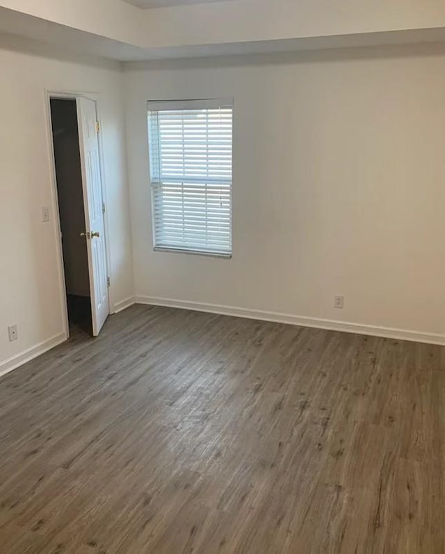 empty room with baseboards and dark wood-style flooring