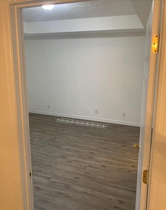 empty room with baseboards and dark wood-style flooring