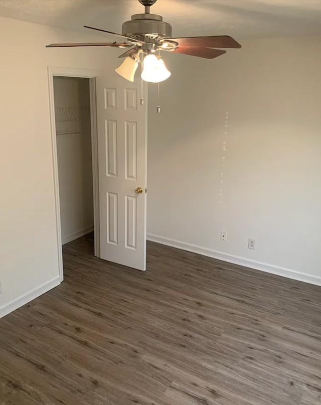 unfurnished bedroom featuring a closet, baseboards, dark wood-type flooring, and a ceiling fan