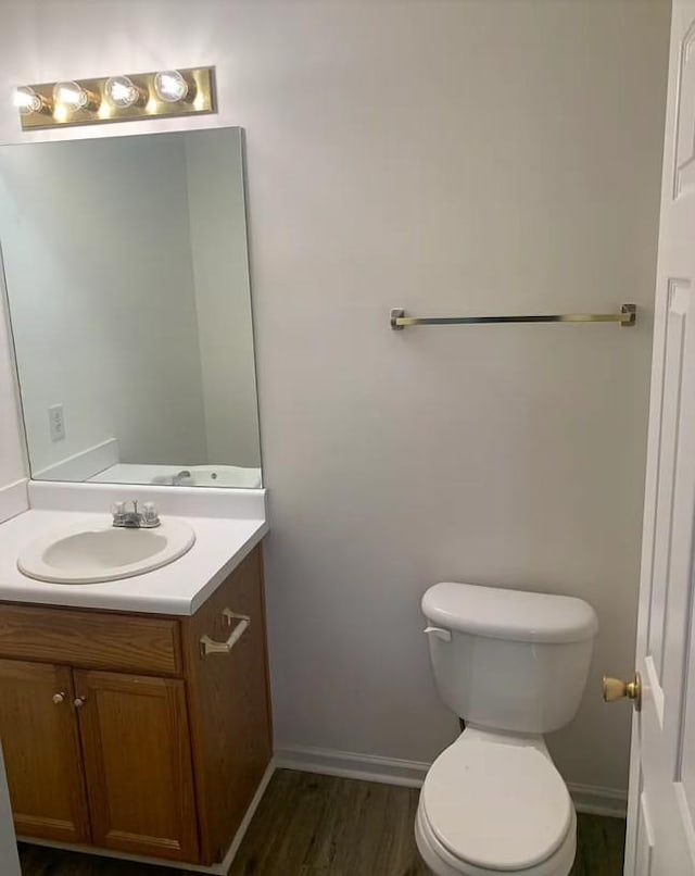 bathroom with toilet, vanity, baseboards, and wood finished floors