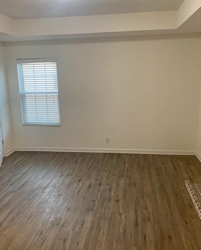 unfurnished room featuring baseboards, dark wood-style flooring, and a textured ceiling