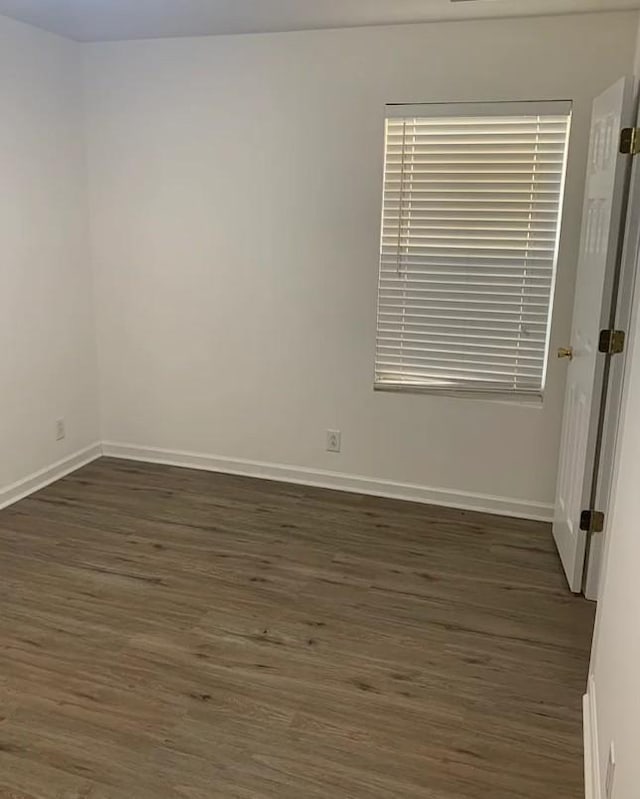 empty room featuring baseboards and dark wood-style flooring