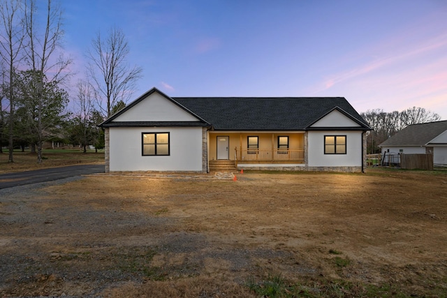 modern farmhouse with a porch and a shingled roof