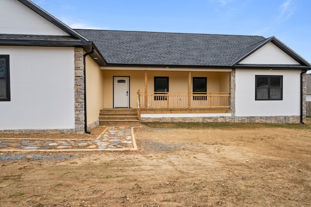 view of front facade featuring a porch, roof with shingles, and stucco siding