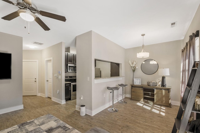 kitchen featuring visible vents, wood finished floors, appliances with stainless steel finishes, baseboards, and ceiling fan