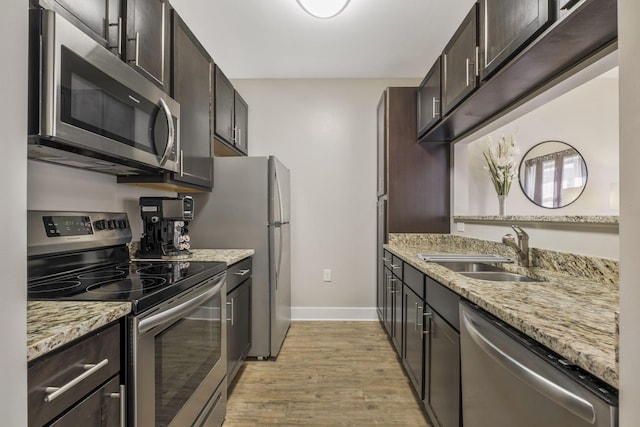 kitchen featuring dark brown cabinets, appliances with stainless steel finishes, light wood-type flooring, and a sink