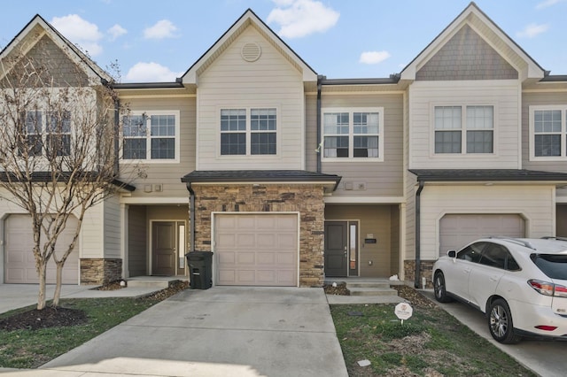 townhome / multi-family property with stone siding, an attached garage, and concrete driveway