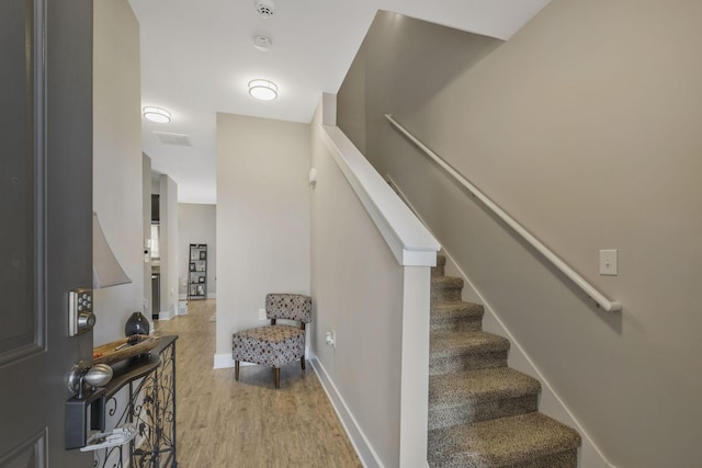 stairway featuring visible vents, wood finished floors, and baseboards