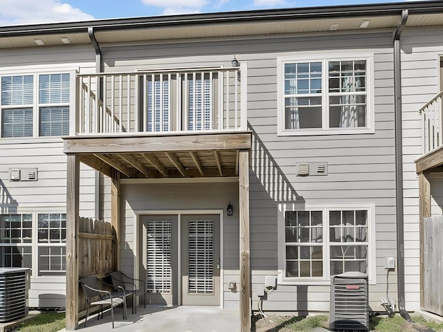 rear view of house featuring a patio area, a balcony, central AC unit, and fence