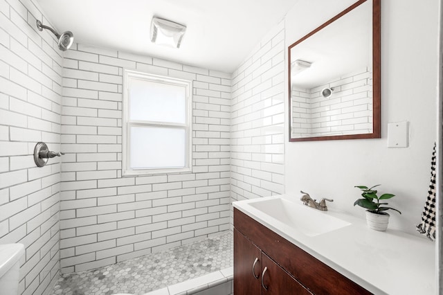 bathroom with vanity, toilet, visible vents, and a tile shower