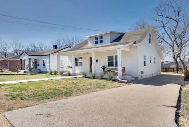 bungalow-style house featuring a front lawn, fence, covered porch, and driveway