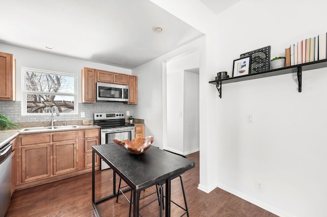 kitchen with a sink, decorative backsplash, light countertops, dark wood-type flooring, and stainless steel appliances