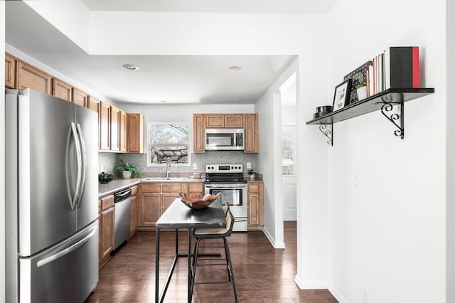 kitchen featuring tasteful backsplash, dark wood finished floors, light countertops, stainless steel appliances, and a sink