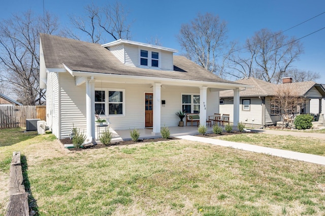 bungalow-style home featuring covered porch, central AC unit, a front lawn, and fence