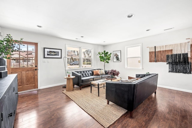 living room featuring a wealth of natural light, visible vents, baseboards, and dark wood-style flooring