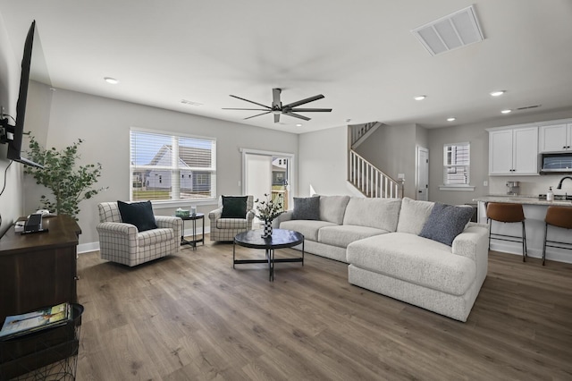 living room with stairs, dark wood-type flooring, recessed lighting, and visible vents
