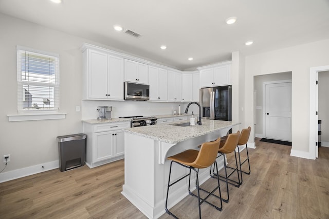 kitchen with a sink, visible vents, white cabinetry, and stainless steel appliances
