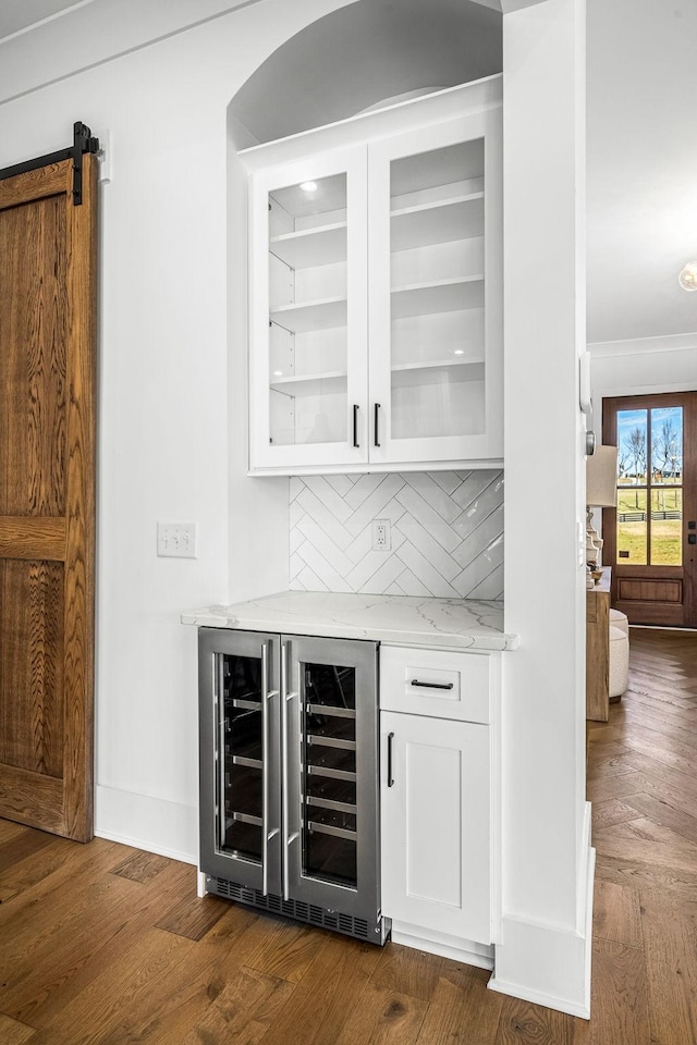 bar with beverage cooler, dark wood-style flooring, backsplash, and ornamental molding