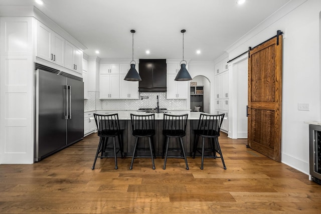 kitchen featuring white cabinets, light countertops, a barn door, and built in fridge