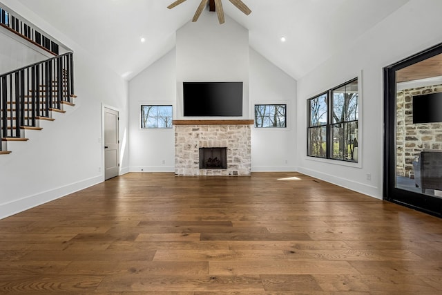 unfurnished living room with a ceiling fan, wood finished floors, a fireplace, and high vaulted ceiling