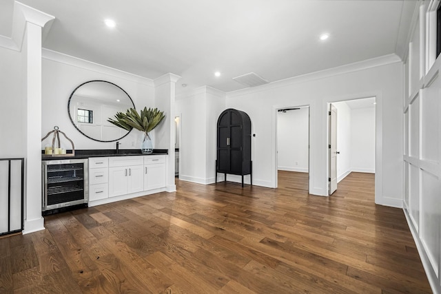 interior space with bar, dark wood-style floors, wine cooler, crown molding, and baseboards