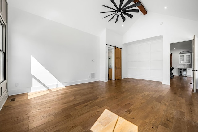 unfurnished living room with visible vents, a barn door, and hardwood / wood-style flooring