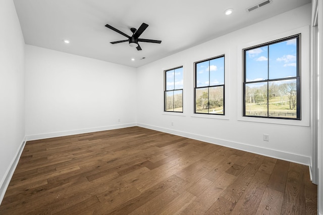 spare room featuring a wealth of natural light, visible vents, baseboards, and dark wood finished floors