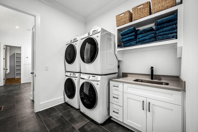 laundry area with stacked washer and dryer, ornamental molding, a sink, cabinet space, and baseboards