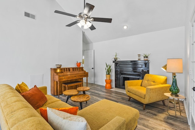 living room featuring visible vents, ceiling fan, a fireplace with flush hearth, vaulted ceiling, and wood finished floors