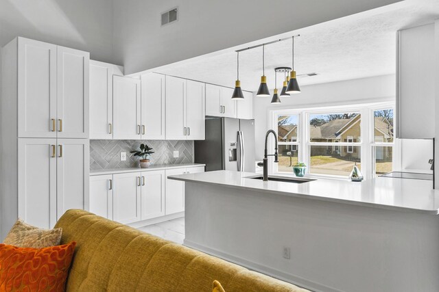 kitchen with white cabinets, visible vents, stainless steel refrigerator with ice dispenser, and a sink