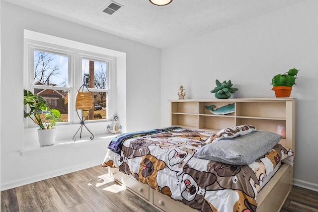 bedroom with visible vents, baseboards, and wood finished floors