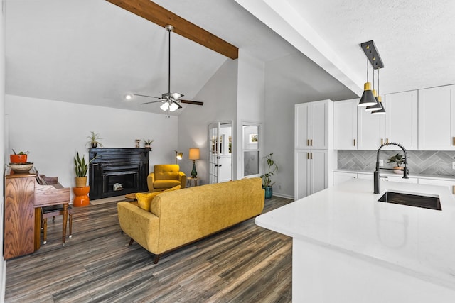 living area featuring ceiling fan, beam ceiling, a fireplace, dark wood-style floors, and high vaulted ceiling