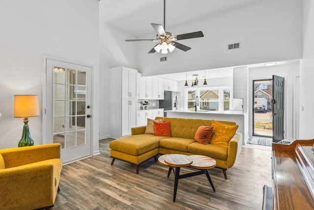 living area with visible vents, a high ceiling, wood finished floors, and a ceiling fan